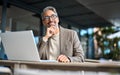 Happy mature business man entrepreneur using laptop outside office looking away. Royalty Free Stock Photo