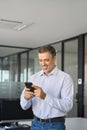 Happy mature business man executive standing in office using mobile phone. Royalty Free Stock Photo