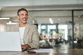 Happy mature business man looking away using laptop in office sitting at desk. Royalty Free Stock Photo