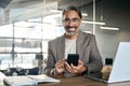 Happy mature business man sitting at office desk using mobile phone. Portrait. Royalty Free Stock Photo