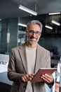 Happy mature business man standing in office using tablet. Vertical portrait Royalty Free Stock Photo