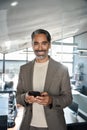 Happy mature business man using cell phone standing in office. Vertical portrait Royalty Free Stock Photo