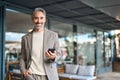 Happy mature business man using mobile cell phone standing outdoors, portrait. Royalty Free Stock Photo