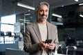 Happy mature business man wearing suit using smartphone in office. Portrait. Royalty Free Stock Photo