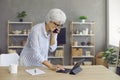 Happy mature business woman working in home office, talking on mobile phone and using tablet Royalty Free Stock Photo