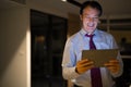 Happy Mature Businessman In Office At Night Using Digital Tablet Computer Royalty Free Stock Photo