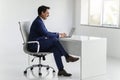 Businessman in blue suit working on a laptop at a minimalist desk in a bright office Royalty Free Stock Photo