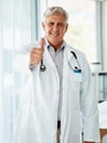 Happy mature caucasian male doctor smiling while showing a thumbs up working at a hospital alone. One senior man wearing Royalty Free Stock Photo