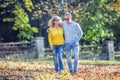 Happy mature couple in autumn park in the embrace walk on the fallen maple leaves Royalty Free Stock Photo