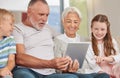 A happy mature couple bonding with their grandchildren while babysitting and using a digital tablet at home Royalty Free Stock Photo