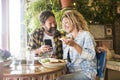 Happy mature couple enjoy dating together at the bar restaurant. Cheerful man and woman adult people using phone during lunch. Royalty Free Stock Photo