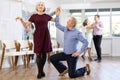 Happy mature couple enjoying retro ballroom dancing in dance salon, man standing on knee and holding hand of woman Royalty Free Stock Photo