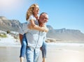 Happy mature couple enjoying vacation by the beach. Active senior husband giving his wife a piggyback ride while Royalty Free Stock Photo