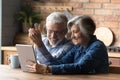 Happy mature couple having fun with tablet, sitting in kitchen Royalty Free Stock Photo