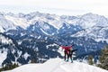 Senior couple is snowshoe hiking in alpine snow winter mountains panorama. Happy successful People with raised arms