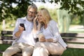 Happy mature couple listening music on smartphone together outdoors in park Royalty Free Stock Photo