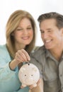 Happy Mature Couple With Piggybank At Home