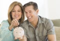 Happy Mature Couple With Piggybank At Home