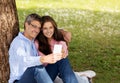 Happy mature couple relaxing in park and using smartphone together Royalty Free Stock Photo