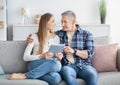 Happy mature couple with tablet pc sitting together on sofa at home, watching video, chatting with friend on webcam Royalty Free Stock Photo