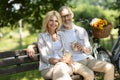 Happy Mature Couple With Takeaway Coffee Relaxing On Bench In Park Royalty Free Stock Photo