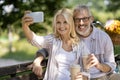 Happy Mature Couple Taking Selfie Outdoors While Sitting On Bench In Park Royalty Free Stock Photo