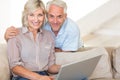 Happy mature couple using laptop on sofa Royalty Free Stock Photo