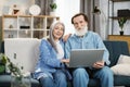 Happy mature couple Using Laptop Watching Movie Together Sitting On Couch At Home. Royalty Free Stock Photo