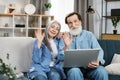 Happy mature couple Using Laptop Watching Movie Together Sitting On Couch At Home. Royalty Free Stock Photo