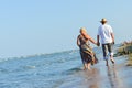 Happy mature couple walking at seashore sandy beach and holding hands Royalty Free Stock Photo