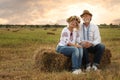 Happy mature couple wearing Ukrainian clothes on hay bale in field Royalty Free Stock Photo