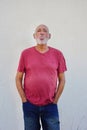 Happy mature elderly man wearing pink shirt and standing against white wall Royalty Free Stock Photo