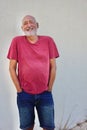 Happy mature elderly man wearing pink shirt and standing against white wall Royalty Free Stock Photo