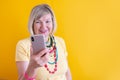 Happy mature elderly senior lady woman talking mobile cell phone in stylish clothes on yellow background Royalty Free Stock Photo