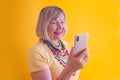 Happy mature elderly senior lady woman talking mobile cell phone in stylish clothes on yellow background Royalty Free Stock Photo