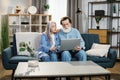 Happy mature family in casual outfit sitting together on couch and using wireless laptop. Royalty Free Stock Photo