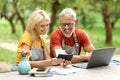 Happy Mature Farmers Couple Accounting Bills With Laptop At Garden Terrace Royalty Free Stock Photo