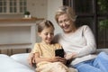 Happy mature grandmother with laughing little granddaughter using smartphone together Royalty Free Stock Photo