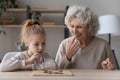 Happy mature grandmother and little granddaughter playing wooden board game Royalty Free Stock Photo