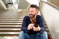 Happy mature guy with cellphone sitting on steps Royalty Free Stock Photo