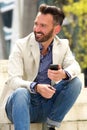 Happy mature guy sitting outdoors with cellphone Royalty Free Stock Photo