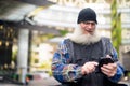 Happy mature handsome bearded man using phone in the city streets outdoors Royalty Free Stock Photo