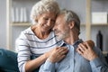 Happy mature husband and wife hug at home couch