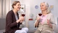 Happy mature ladies talking holding wine glasses, friendship togetherness, rest