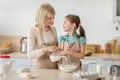 Happy mature lady and her granddaughter kneading dough Royalty Free Stock Photo