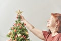 Happy woman smiling as she puts a gold star on the top of a Christmas tree Royalty Free Stock Photo