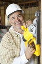 Happy mature male construction worker cutting wood with a circular saw