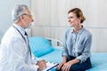 happy mature male doctor writing in clipboard near female patient Royalty Free Stock Photo