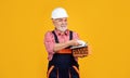happy mature man bricklayer in helmet on yellow background