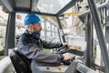 Happy mature man fork lift truck driver lifting pallet in storage warehouse . Royalty Free Stock Photo